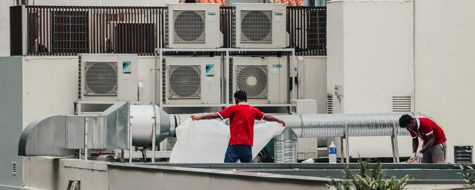 Equipe trabalhando entre equipamentos de climatização na cobertura de um prédio